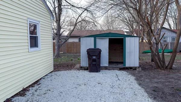 a view of a small house with a yard and large tree