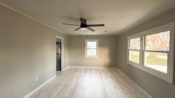 a view of empty room with wooden floor and fan