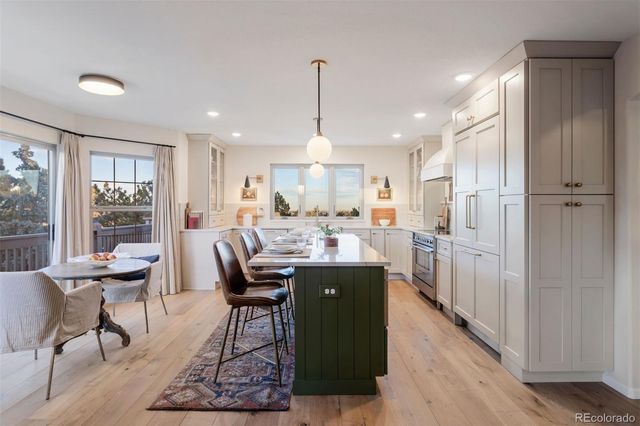 a dining hall with stainless steel appliances granite countertop a dining table chairs and a refrigerator