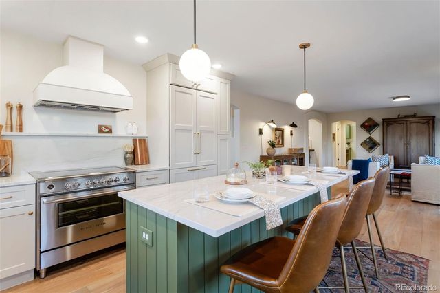 a kitchen with a stove a sink a dining table and chairs with wooden floor