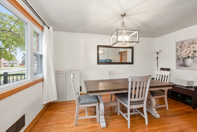 a dining room with wooden floor a chandelier a wooden table and chairs