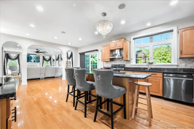 a kitchen with stainless steel appliances granite countertop a stove a sink dishwasher a dining table and chairs with wooden floor