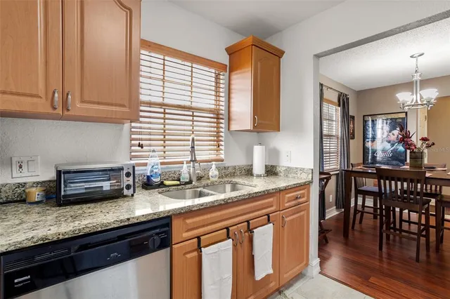 a kitchen with stainless steel appliances granite countertop a sink a stove a dining table and chairs