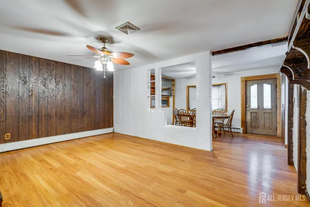 a view of an empty room with window and wooden floor
