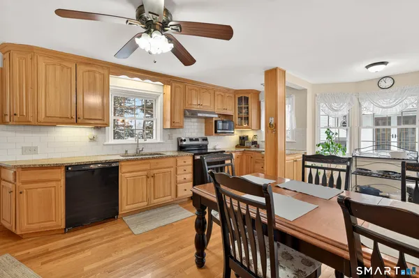 a kitchen with stainless steel appliances granite countertop a stove a refrigerator a kitchen island a sink dishwasher a dining table and chairs with wooden floor