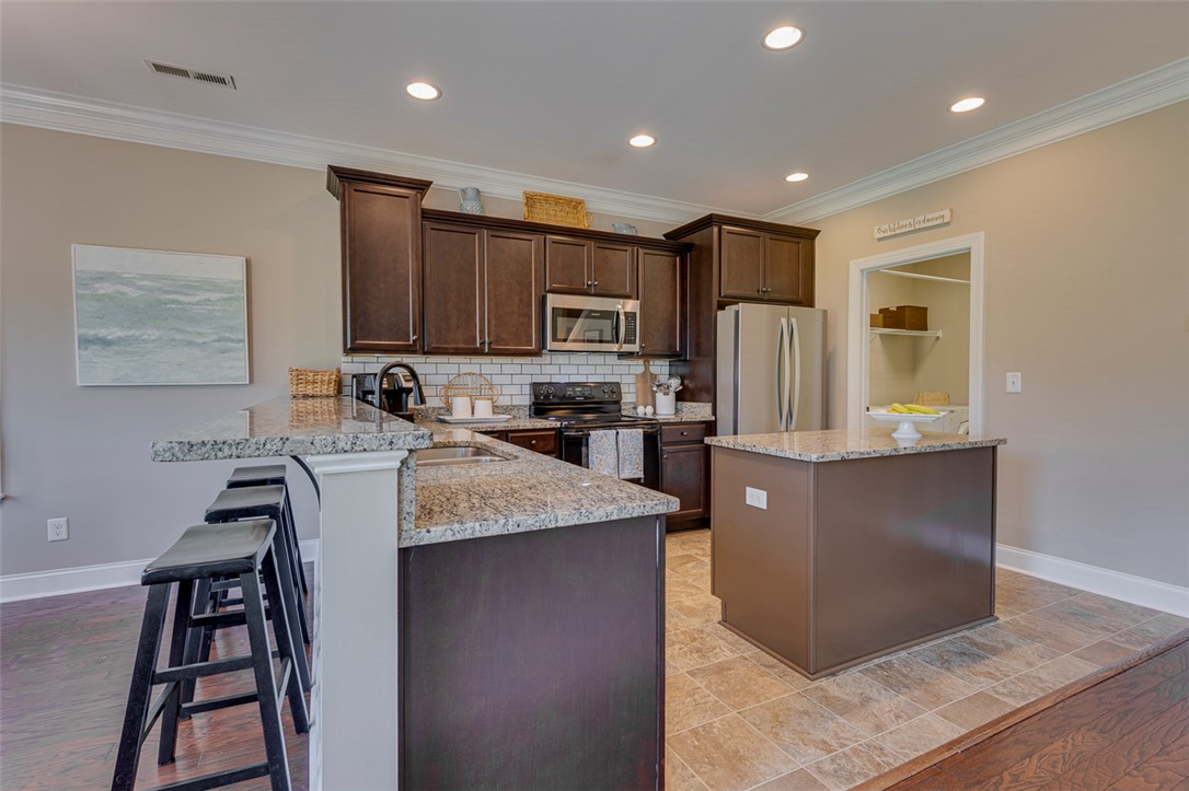 203 Streams Way Anderson, SC 29625 - Photo 19 of 47 This modern kitchen features rich cabinetry, gleaming countertops, and an inviting island for culinary pursuits.