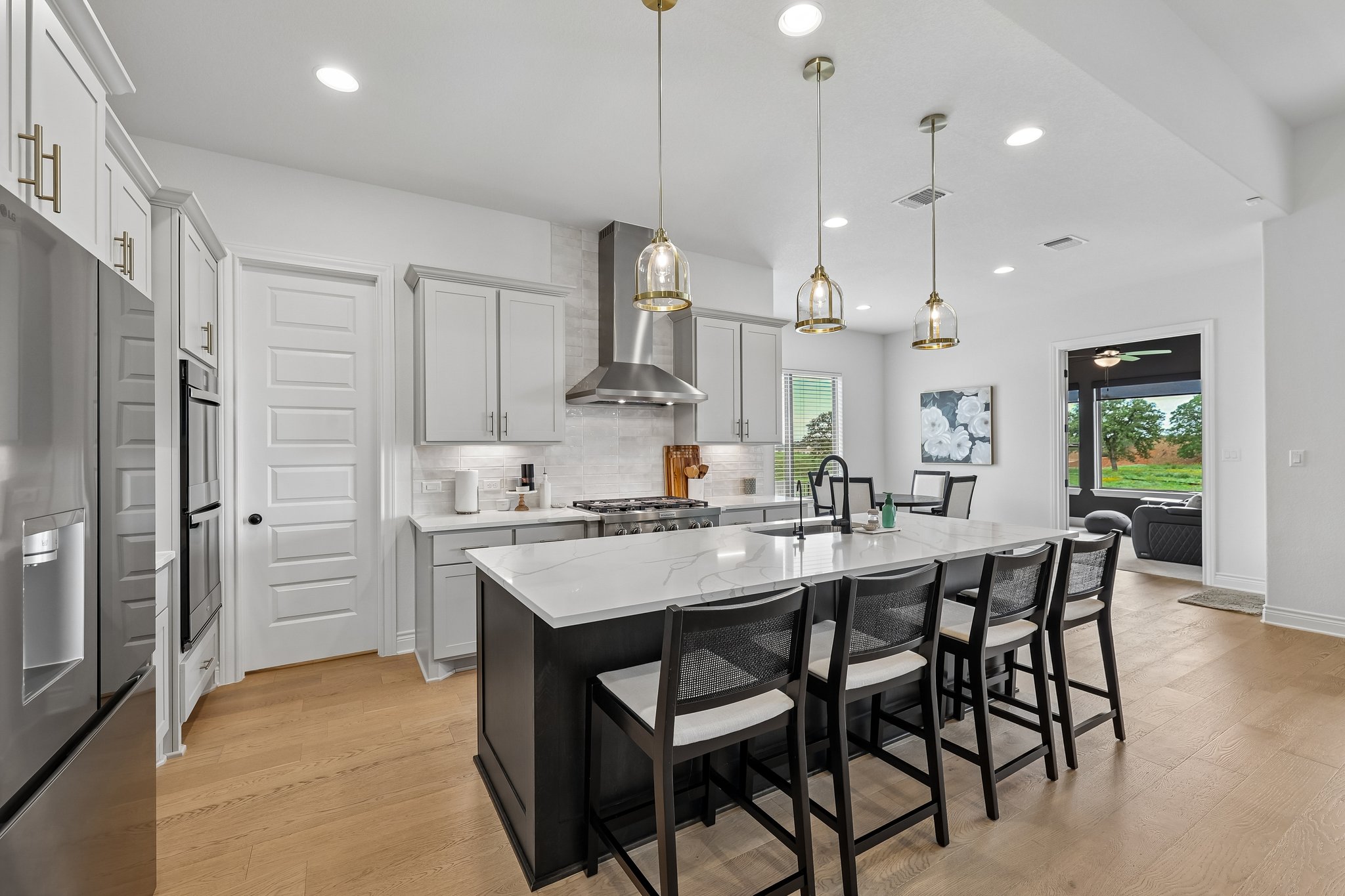 130 Firethorn Loop Bastrop, TX 78602 - Photo 10 of 38 Gourmet kitchen featuring a large central island with seating, stainless steel appliances, light wood-finish flooring, recessed lighting, and pendant fixtures
