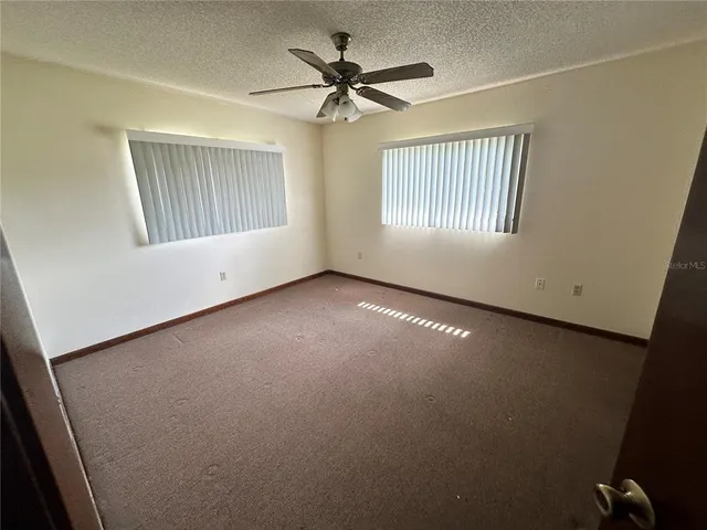 an empty room with windows and fan