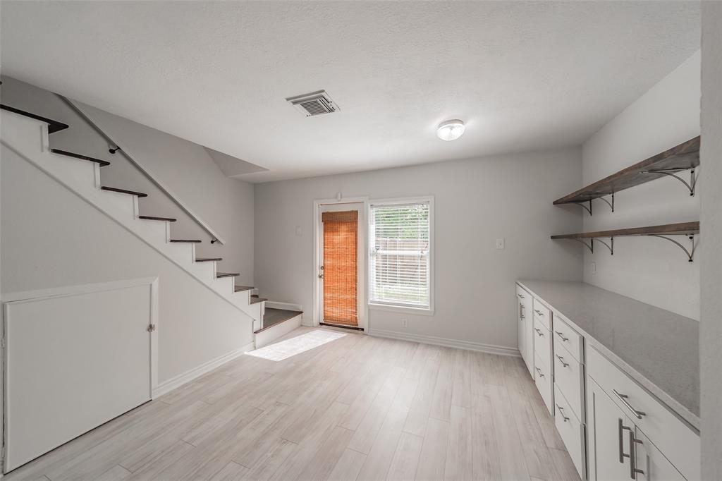 193 Merlin Way Euless, TX 76039 - Photo 14 of 35 Bright interior space featuring light wood-finish flooring, a contemporary staircase with dark treads, and a built-in storage unit under the stairs. Back door leads to enclosed patio.