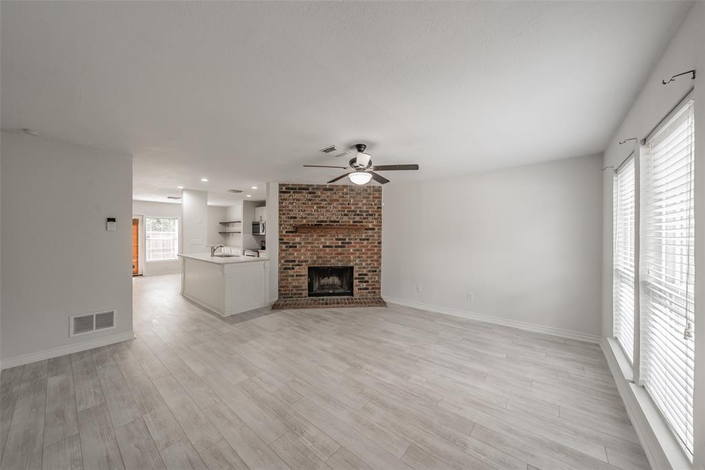 193 Merlin Way Euless, TX 76039 - Photo 2 of 35 Spacious living room featuring corner fireplace, ceiling fan, and vinyl wood look floors.