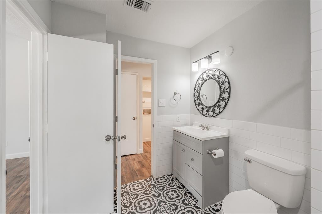 193 Merlin Way Euless, TX 76039 - Photo 28 of 35 Bathroom featuring a gray vanity, black and white patterned floor tiles, and a white subway tile wainscoting