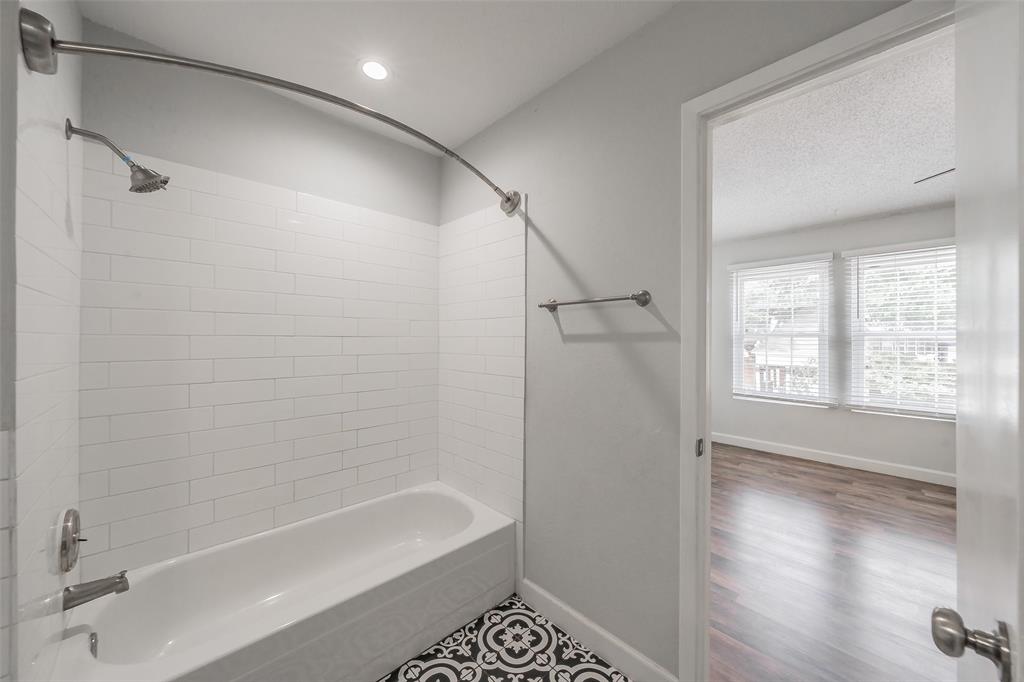 193 Merlin Way Euless, TX 76039 - Photo 31 of 35 Bathtub with white subway tile surround, patterned floor tile, and brushed nickel fixtures