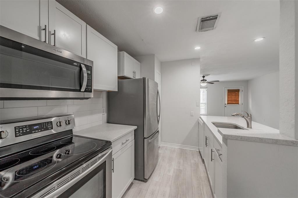 193 Merlin Way Euless, TX 76039 - Photo 8 of 35 Modern kitchen featuring stainless steel appliances, white flat-panel cabinetry, & white subway tile backsplash.
