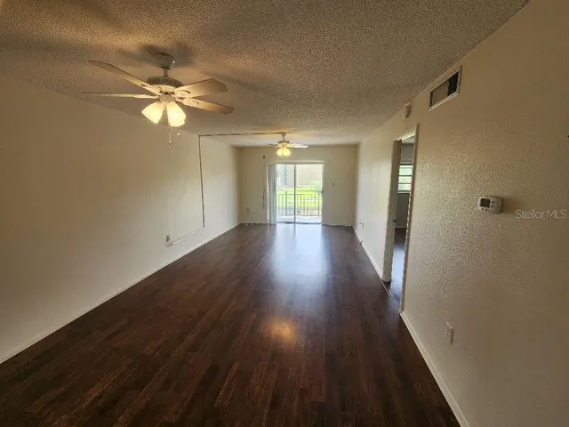a view of empty room with wooden floor and fan