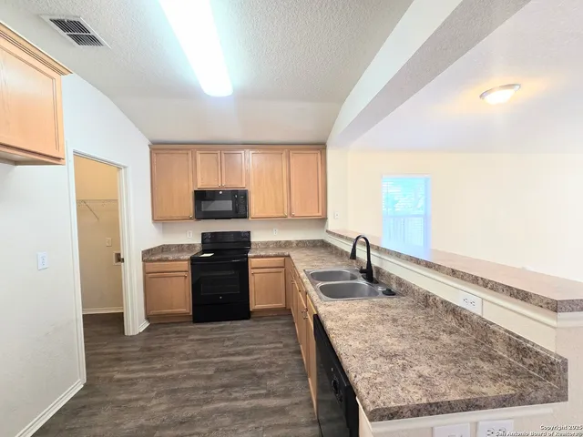 a kitchen with granite countertop a stove top oven a sink and dishwasher a refrigerator with wooden floor