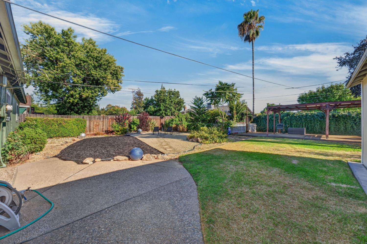 3708 Merrily Way Sacramento, CA 95821 - Photo 1 of 51 Expansive backyard featuring a lush lawn, concrete patio, a wooden pergola, mature trees, and landscaped garden beds