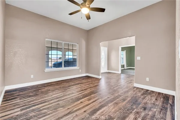 an empty room with chandelier fan and windows