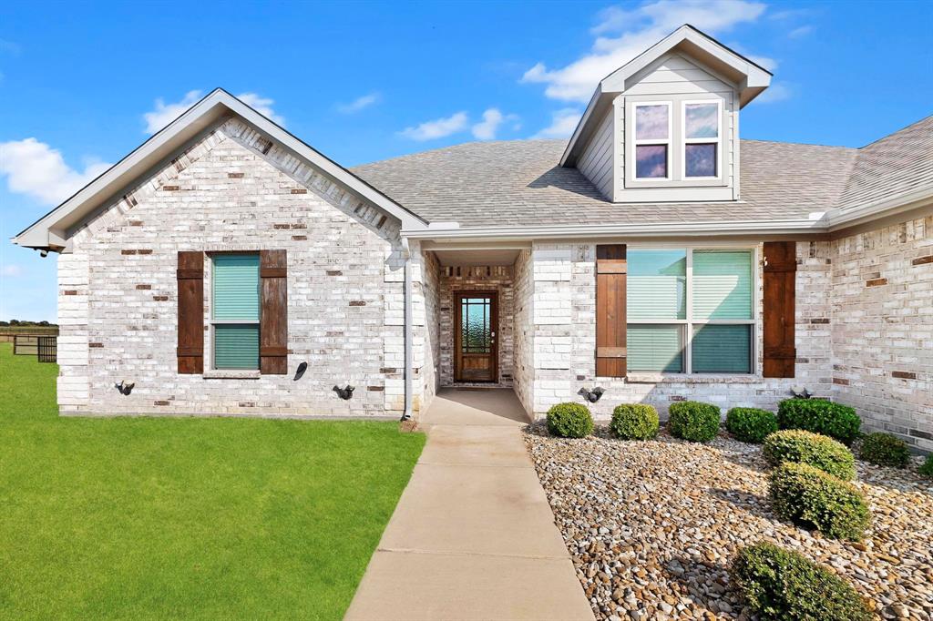 634 Gant Road Sherman, TX 75090 - Photo 10 of 40 Brick and stone exterior featuring a dormer window, wood-finish shutters, a covered entryway, a walkway, and landscaped rock beds