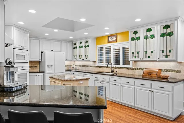a kitchen with stainless steel appliances granite countertop a stove a sink and white cabinets