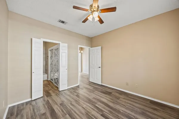 an empty room with wooden floor chandelier fan and windows