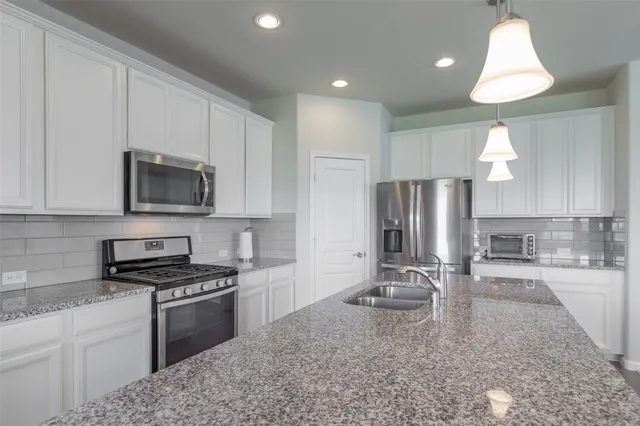 a kitchen with granite countertop a sink a counter top space appliances and cabinets