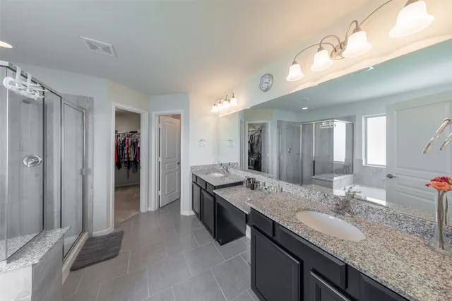 a bathroom with a granite countertop double vanity sink and a mirror