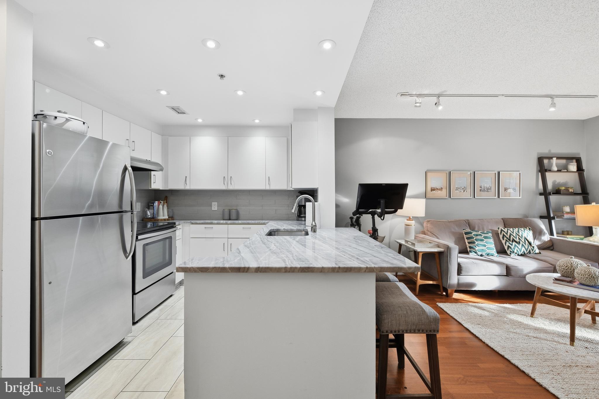 2301 N Street Northwest, Unit 212 Washington, DC 20037 - Photo 6 of 23 a kitchen with kitchen island a counter top space a sink stainless steel appliances and cabinets