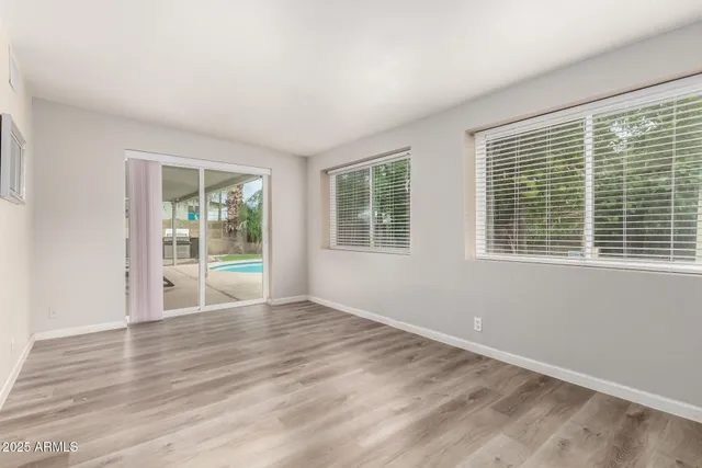 a view of an empty room with wooden floor and windows