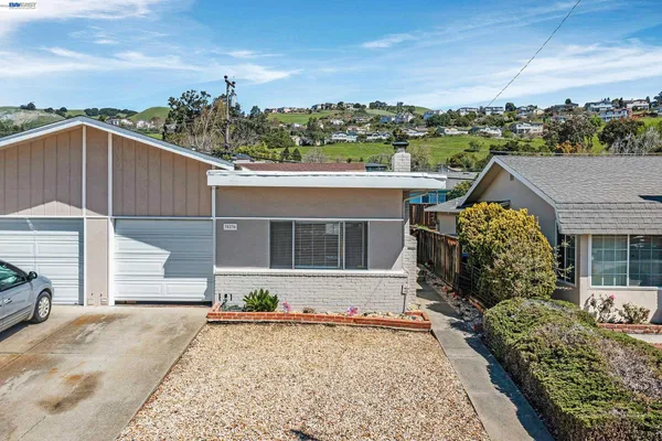 a front view of a house with a garden and mountain view