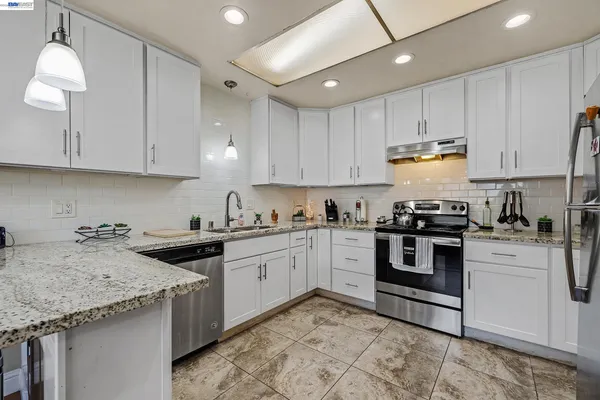 a kitchen with granite countertop sink stainless steel appliances and white cabinets