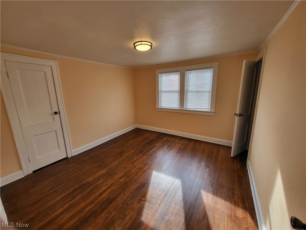 955 Nela View Road Cleveland Heights, OH 44112 - Photo 11 of 34 Spare room featuring dark hardwood / wood-style flooring, crown molding, and a textured ceiling