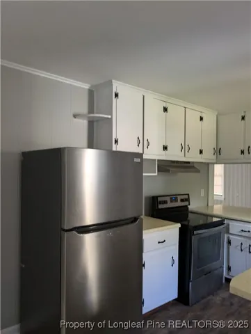 a view of a refrigerator in kitchen and white cabinets