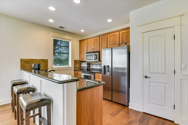 a kitchen with stainless steel appliances granite countertop a refrigerator a sink a stove and a refrigerator