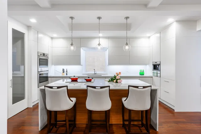 a kitchen with stainless steel appliances a dining table chairs and white cabinets