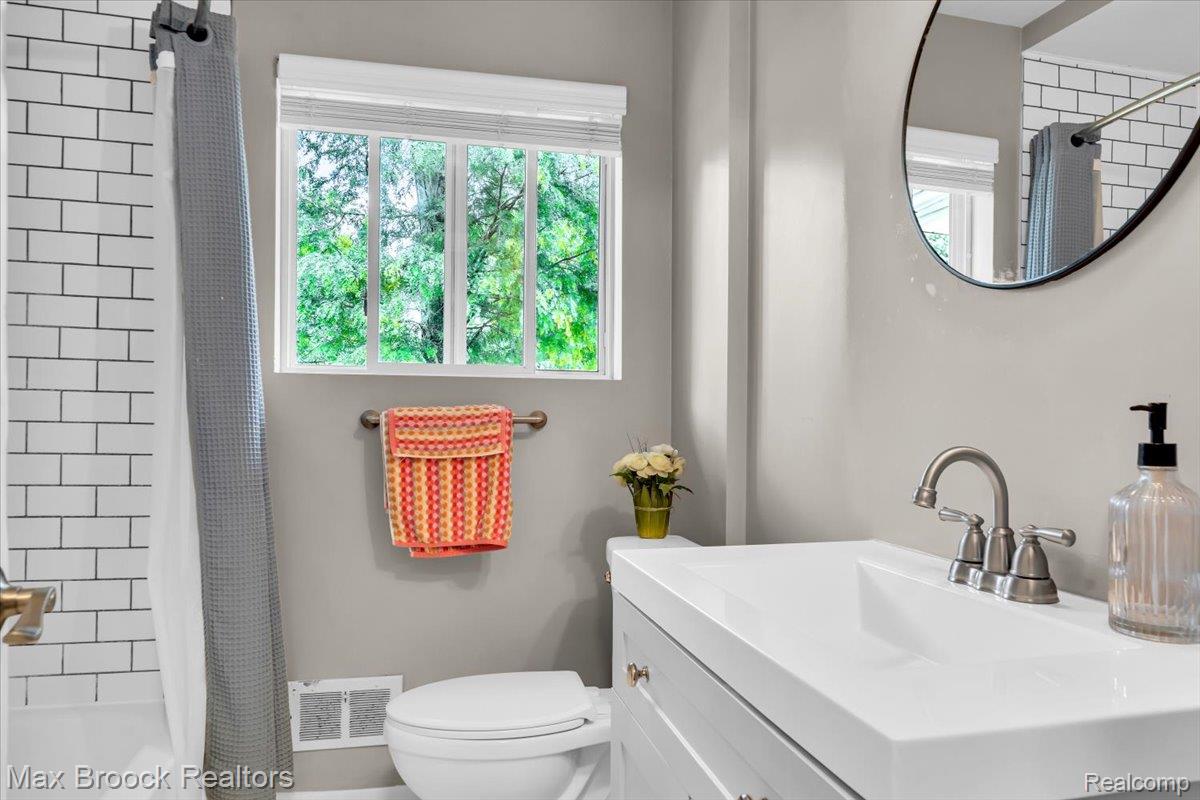 28403 Peppermill Road Farmington, MI 48331 - Photo 20 of 33 Bathroom featuring a vanity with an integrated sink, a circular wall mirror, and a window