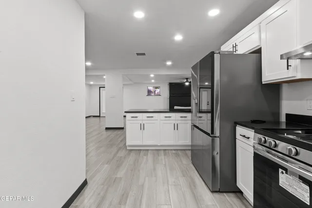 a kitchen with a refrigerator and white cabinets