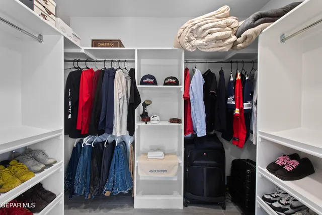 a view of walk in closet with clothes and shoes