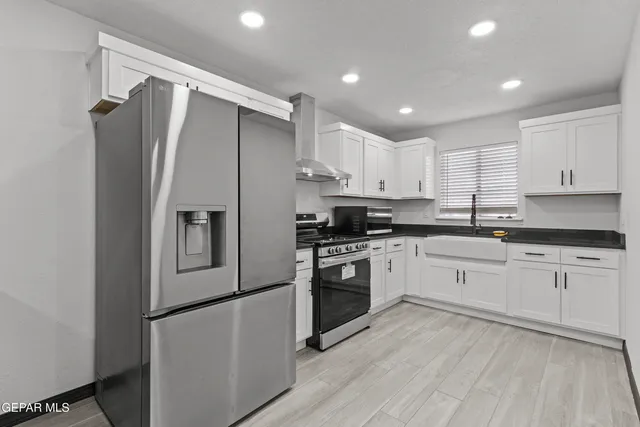 a kitchen with stainless steel appliances granite countertop a refrigerator sink and white cabinets