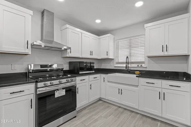 a kitchen with stainless steel appliances granite countertop white cabinets and a stove a oven with white countertops