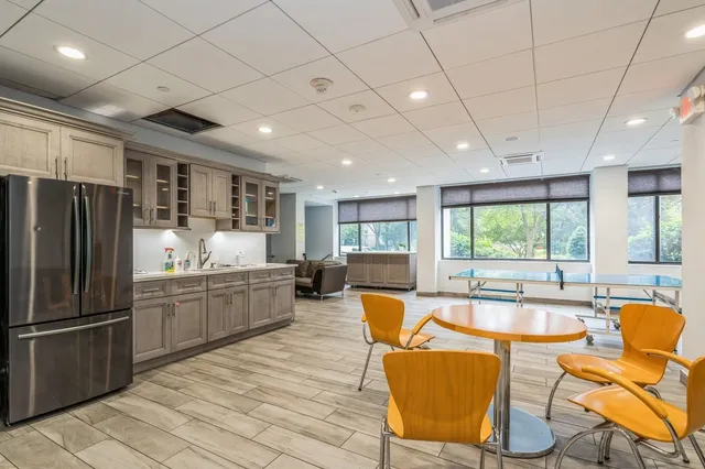 a kitchen with stainless steel appliances granite countertop a refrigerator a sink dishwasher a dining table and chairs with wooden floor