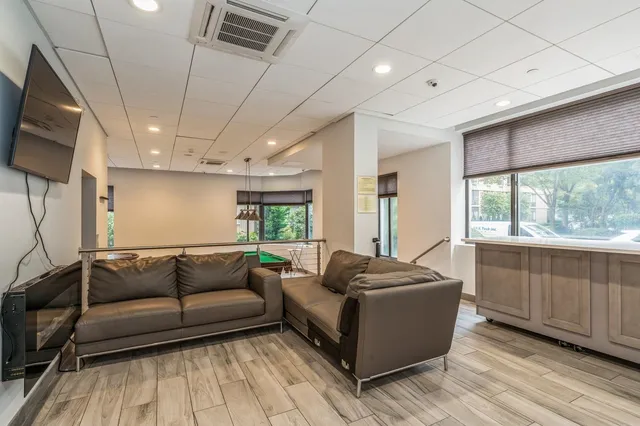 a living room with furniture a flat screen tv and floor to ceiling window