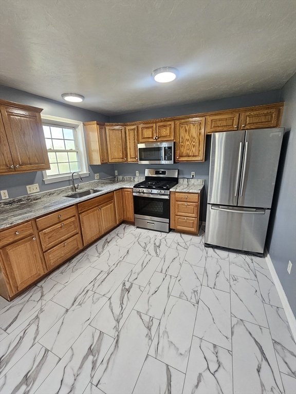 40 Merrick Street, Unit A Worcester, MA 01609 - Photo 31 of 32 a kitchen with stainless steel appliances granite countertop a sink stove and refrigerator