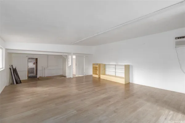 a view of an empty room with window and wooden floor