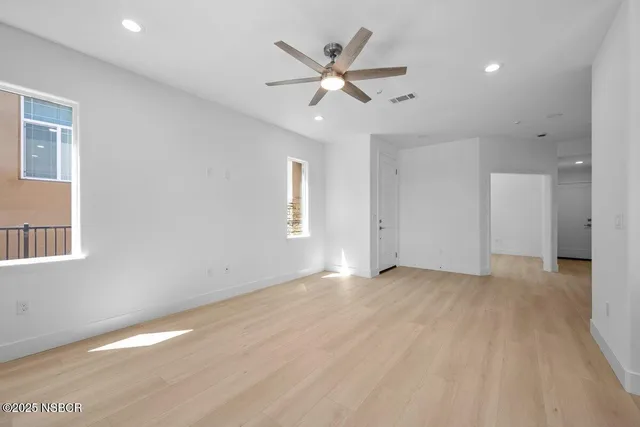 a view of an empty room with window and wooden floor