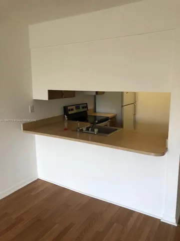 a kitchen with a sink and a stove with wooden floor