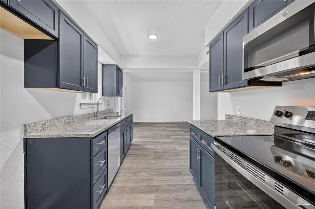 1801 East Grauwyler Road, Unit 101 Irving, TX 75061 - Photo 12 of 39 a kitchen with granite countertop stainless steel appliances and wooden cabinets