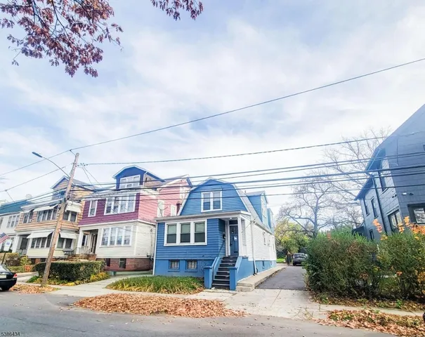 a front view of a residential apartment building with a yard and potted plants