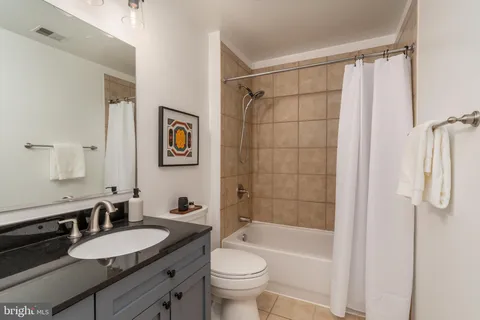 a bathroom with a granite countertop sink toilet a mirror a vanity and shower