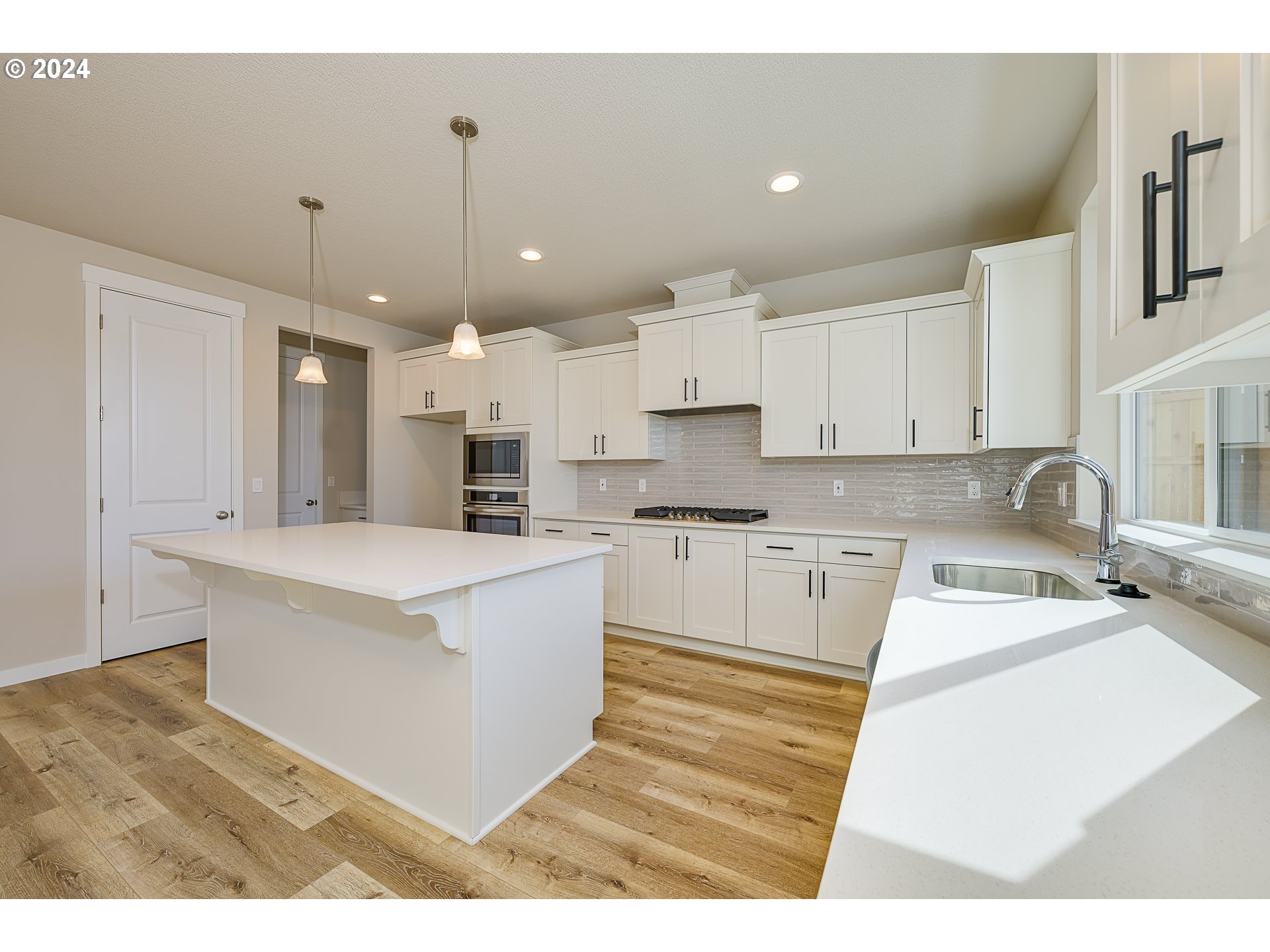 18660 Warm Springs Street, Unit 10 Sandy, OR 97055 - Photo 9 of 42 a large white kitchen with kitchen island a stove a sink a refrigerator and white cabinets