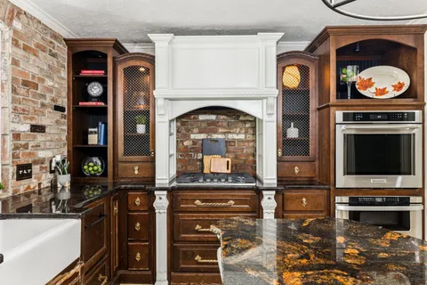 a kitchen with stainless steel appliances granite countertop a stove and a view of living room